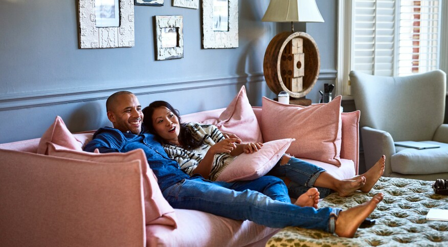 Couple at home watching television together on sofa