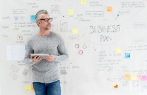 Thoughtful man creating a business plan and using a tablet computer