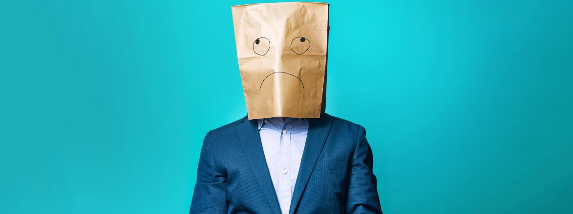 photo of man with paper bag over his head that has sad face drawn on it