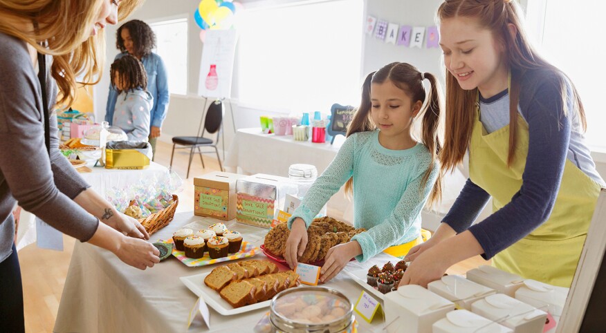 Mom and girls setting up for a bake sale