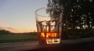 Close-up of whiskey glass on ledge during sunset 