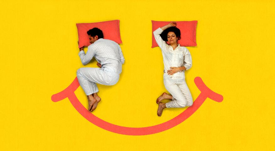 Couple sleeping separately in bed with smiley face background