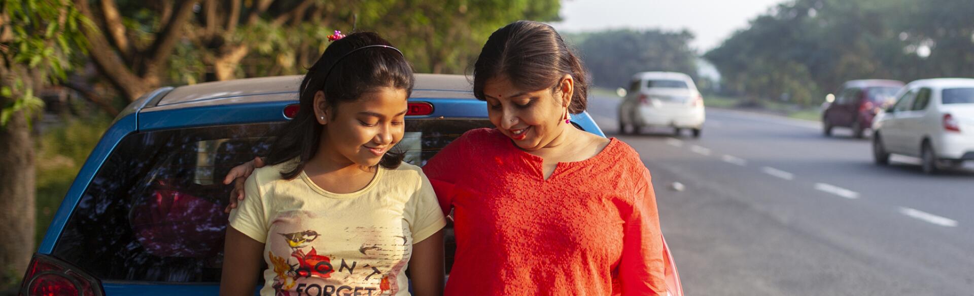 Mother And Daughter Standing Beside A Highway And Interacting