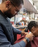 Mature Black woman getting haircut in barber's chair