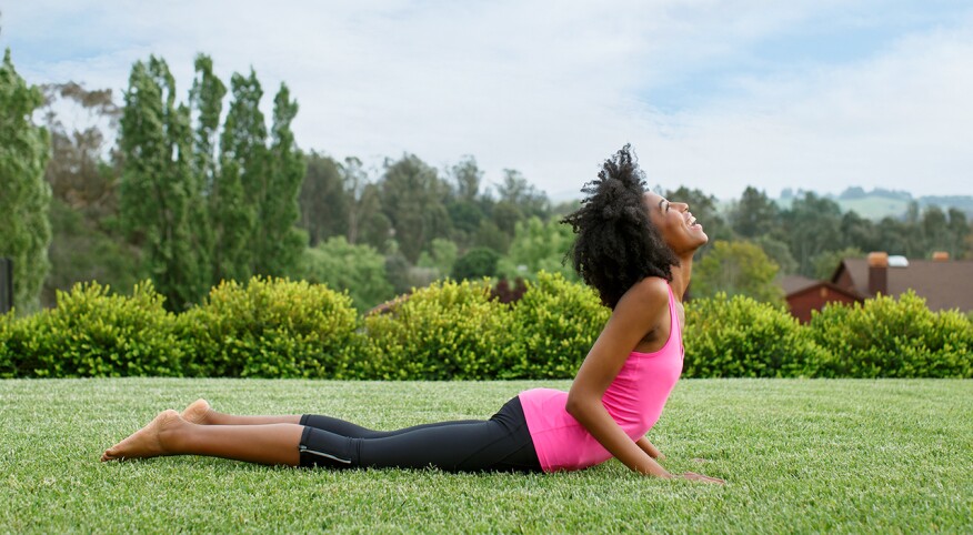 Woman doing yoga outside to help with perimenopause pain.