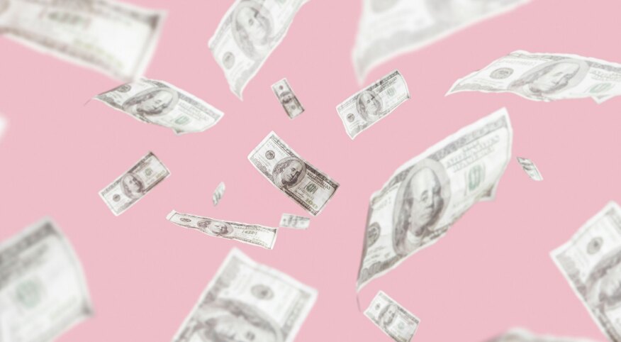 Money on a pink backdrop floating in the air