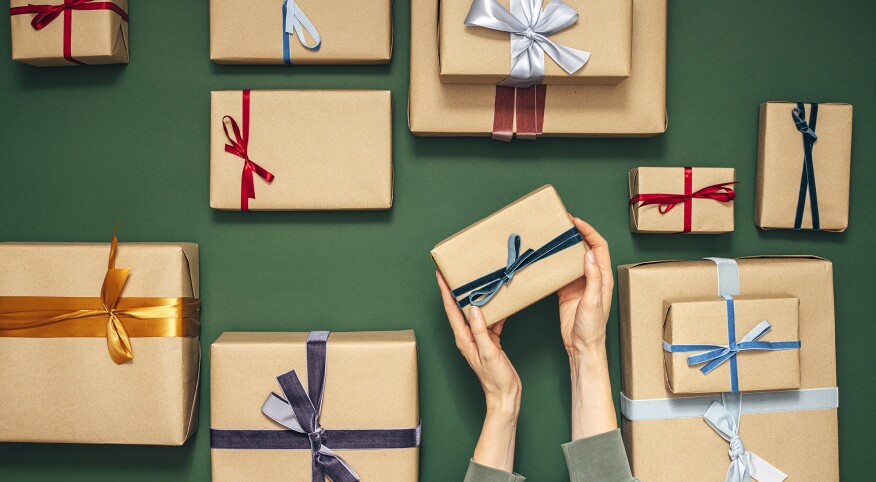 Anonymous Person Holding One of Many Gift Boxes on a Green Background