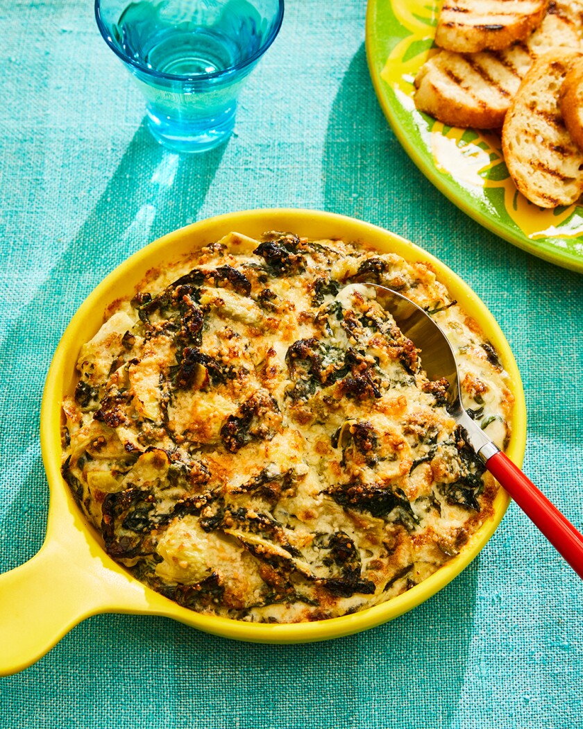Marcia Kester Doyle’s Spinach and Artichoke dip in a yellow ceramic dish on a teal background