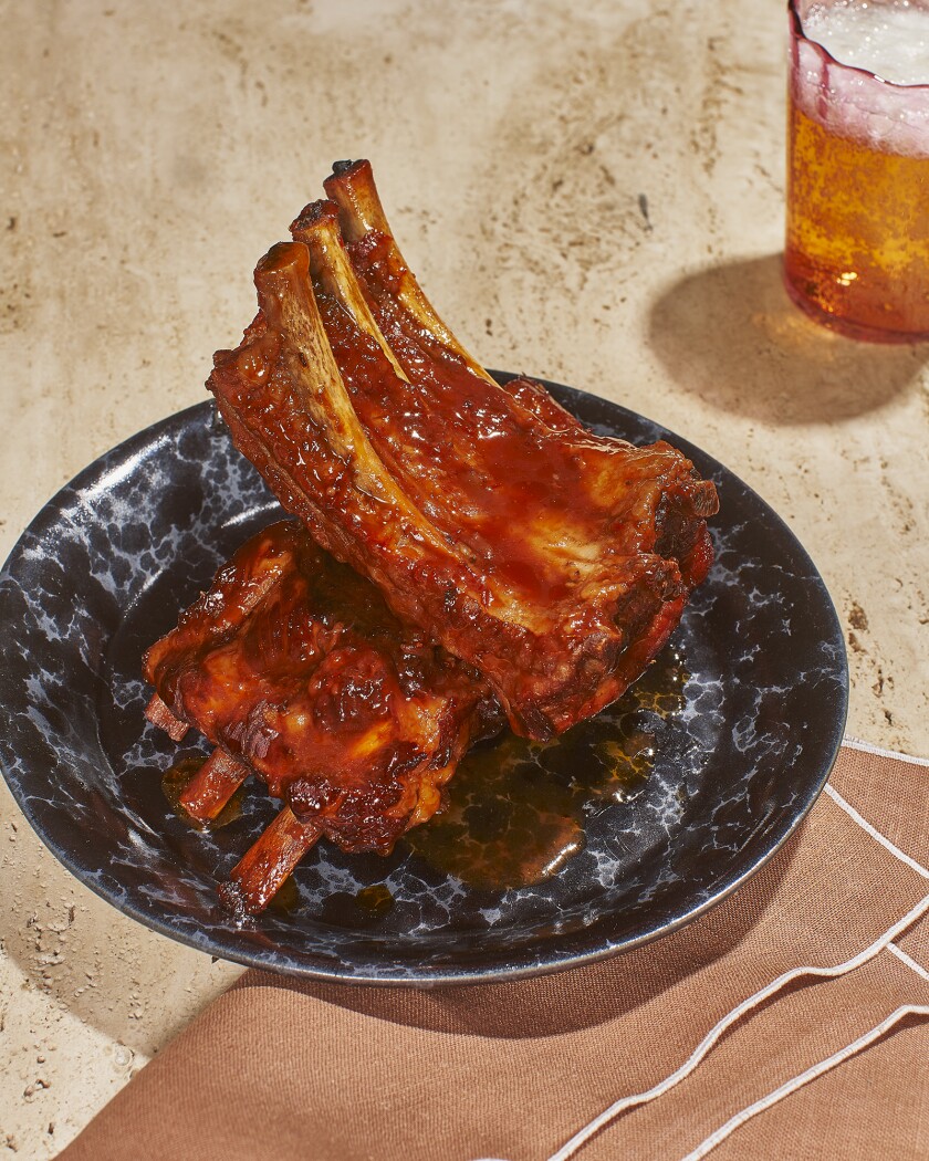 Baby back ribs on black plate with a side of beer