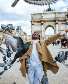 France, Paris, Happy young woman with flying pigeons at Arc de Triomphe