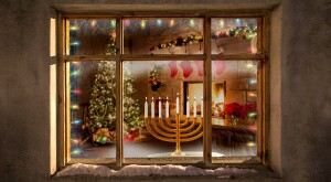 Looking inside a window from outside showing a Christmas tree, stockings, and a menorrah.