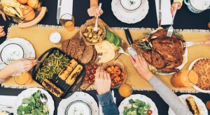 Overhead shot of hands reaching out for Thanksgiving dinner