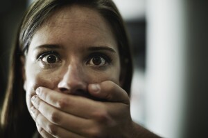 A terrified young woman held captive by a man with his hand over her mouth