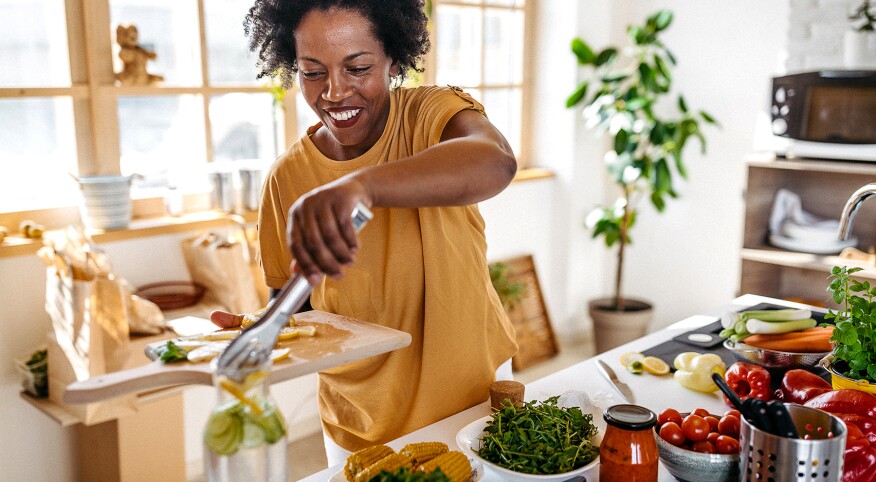 Happy African woman making a lemonade at home