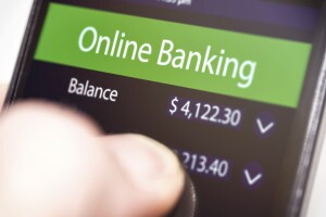Close-up of hand holding a modern smartphone with a generic mobile banking app running. The app interface is non existing one. It has been created in graphic program by contributor