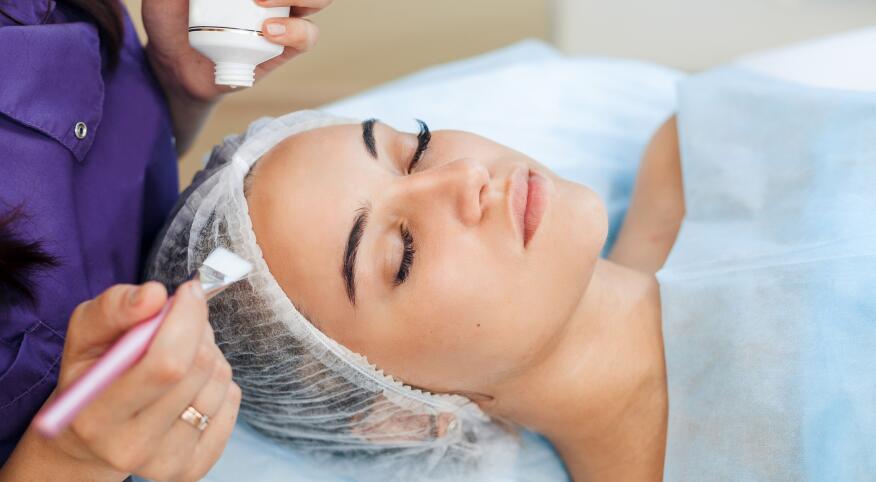 woman getting chemical peel done by cosmetologist