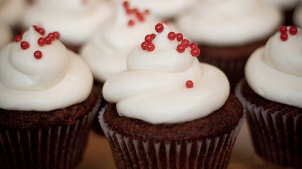 A close up of red velvet cupcakes with cream cheese frosting and red sprinkles