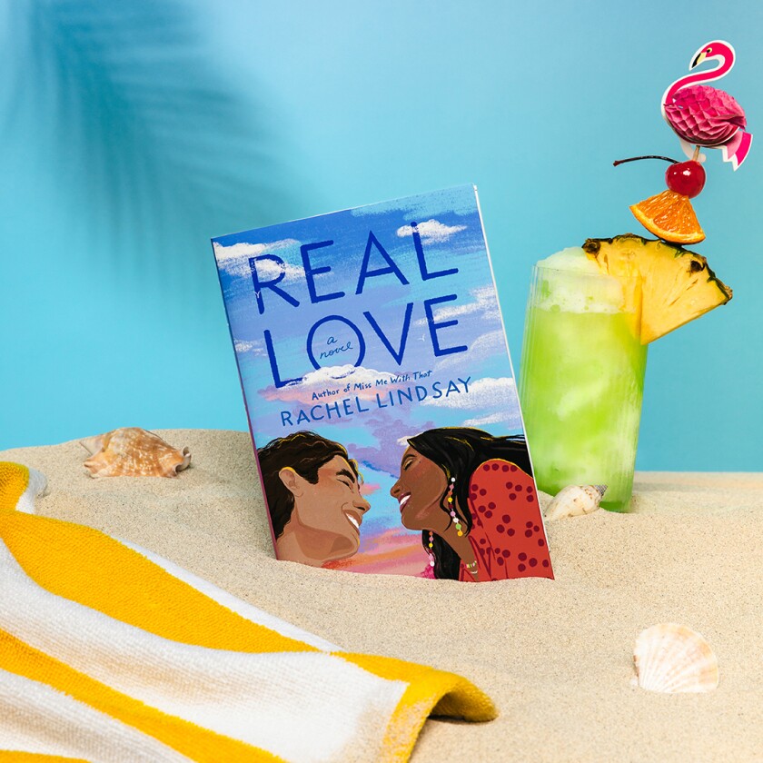 Book styled in pile of sand with beach accessories