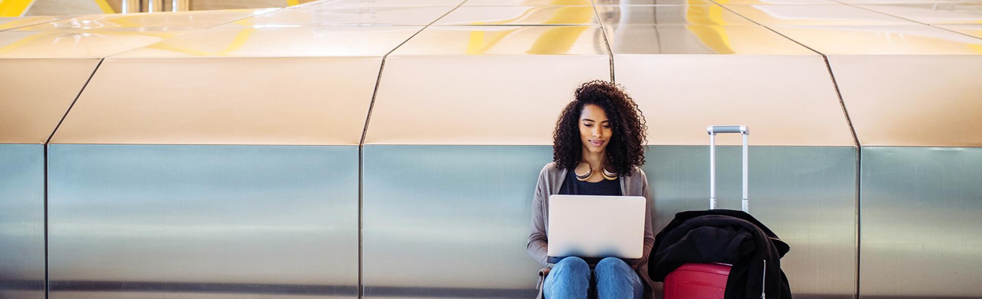 attractive black Woman at the airport sitting and working with laptop