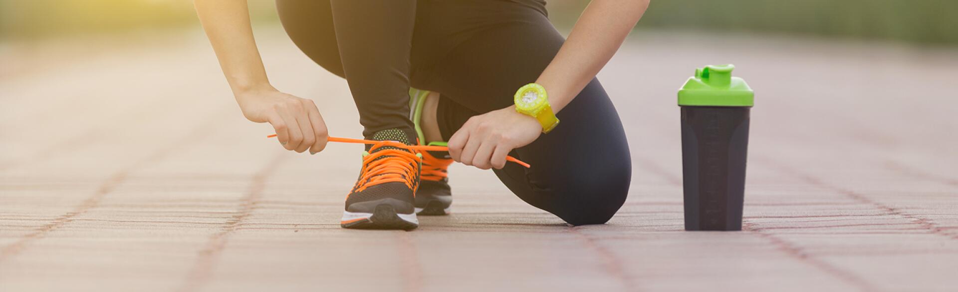 woman tying her shoe while exercising