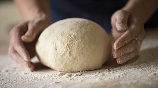 A close up of hands shaping bread dough