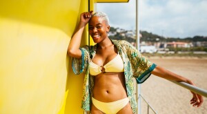 Woman in a yellow bikini lays at the beach