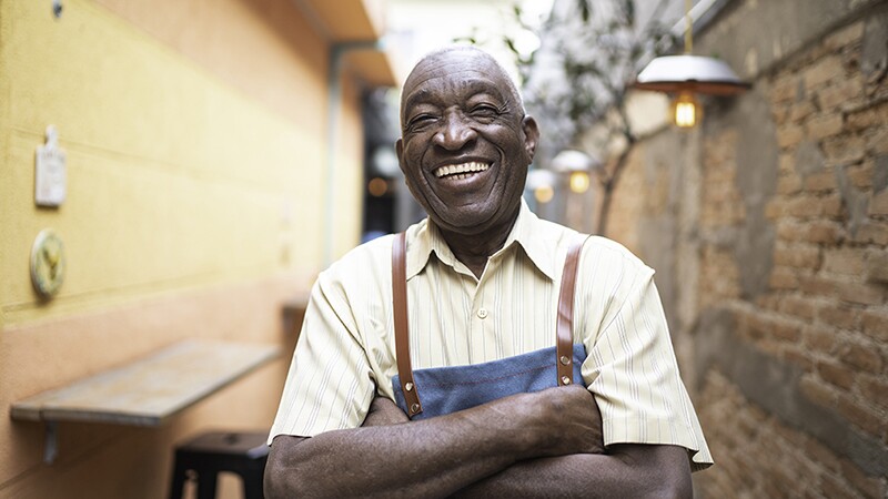 A smiling waiter standing outside