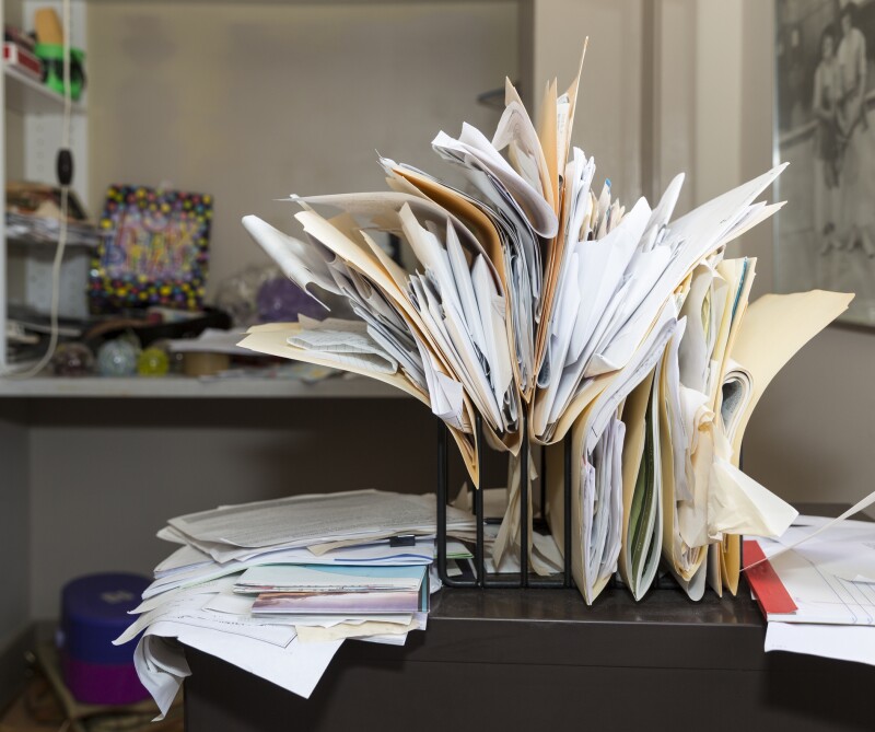 Messy, chaotic, file rack on a desk in cluttered room