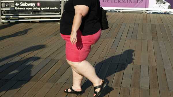 An obese woman walks on the boardwalk
