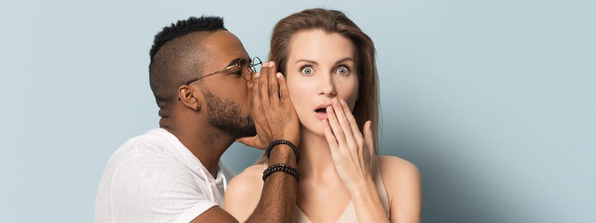 African American man tell secret to shocked caucasian female