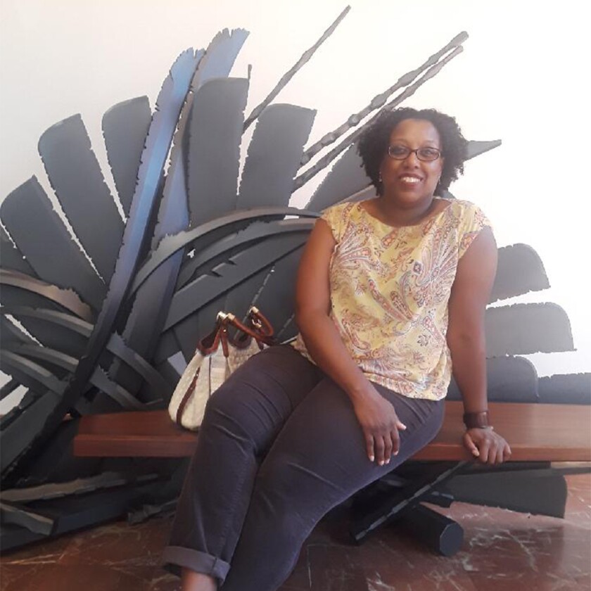 Kesha Lindsay sitting in front of a sculpture