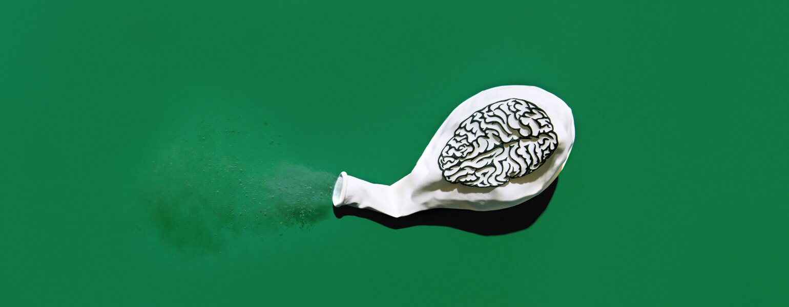 Deflated white balloon blowing out dust with a print of a brain on the balloon.