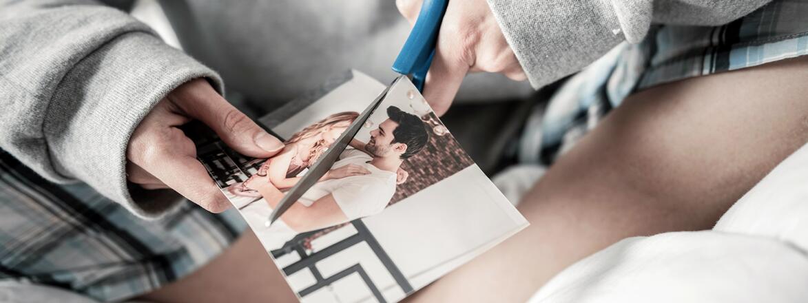 woman cutting photo of her and her ex in half