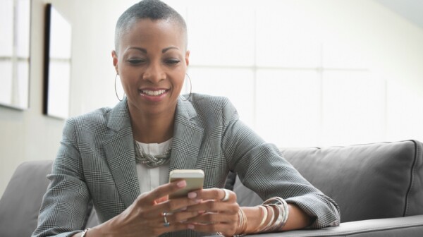 Black businesswoman using cell phone on sofa in office