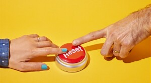 Female and male hand pressing a reset button together