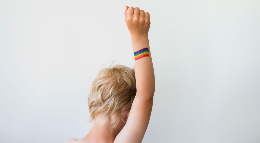 Raised child hand with rainbow LGBTQ pride flag tattoo