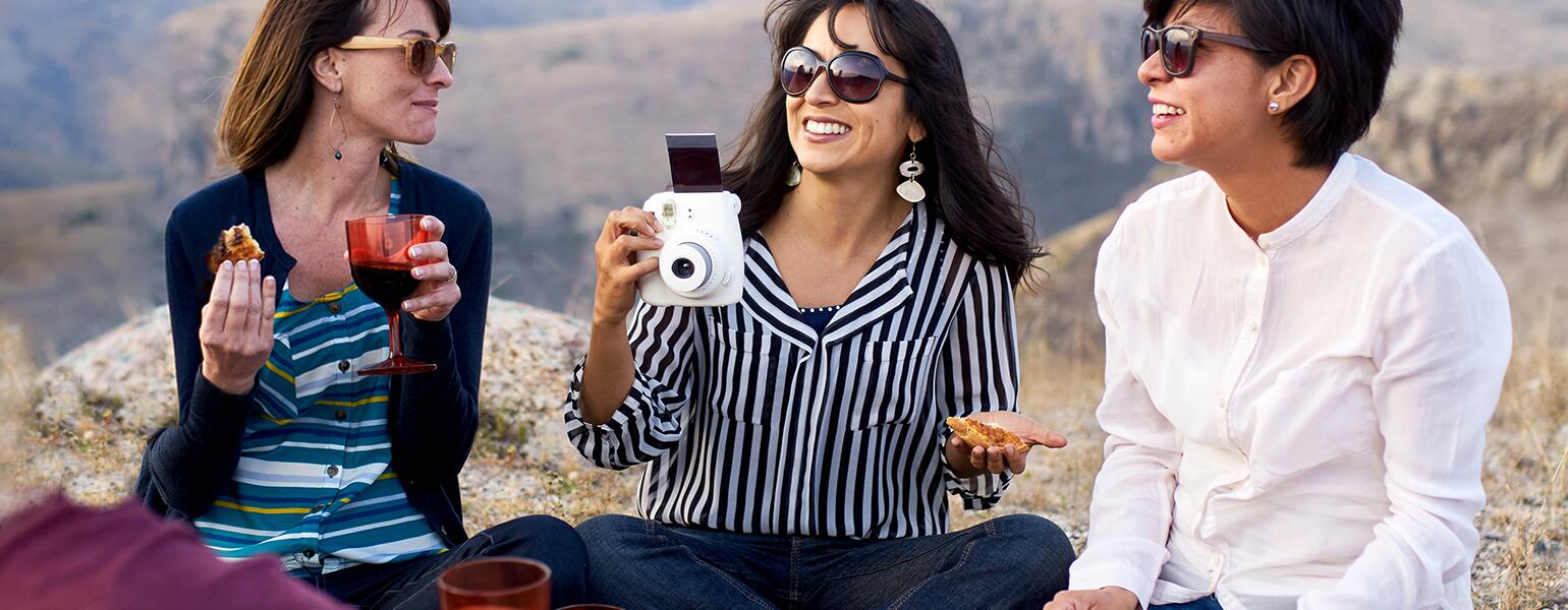 A group of new friends sit outdoors during a picnic in the mountains.
