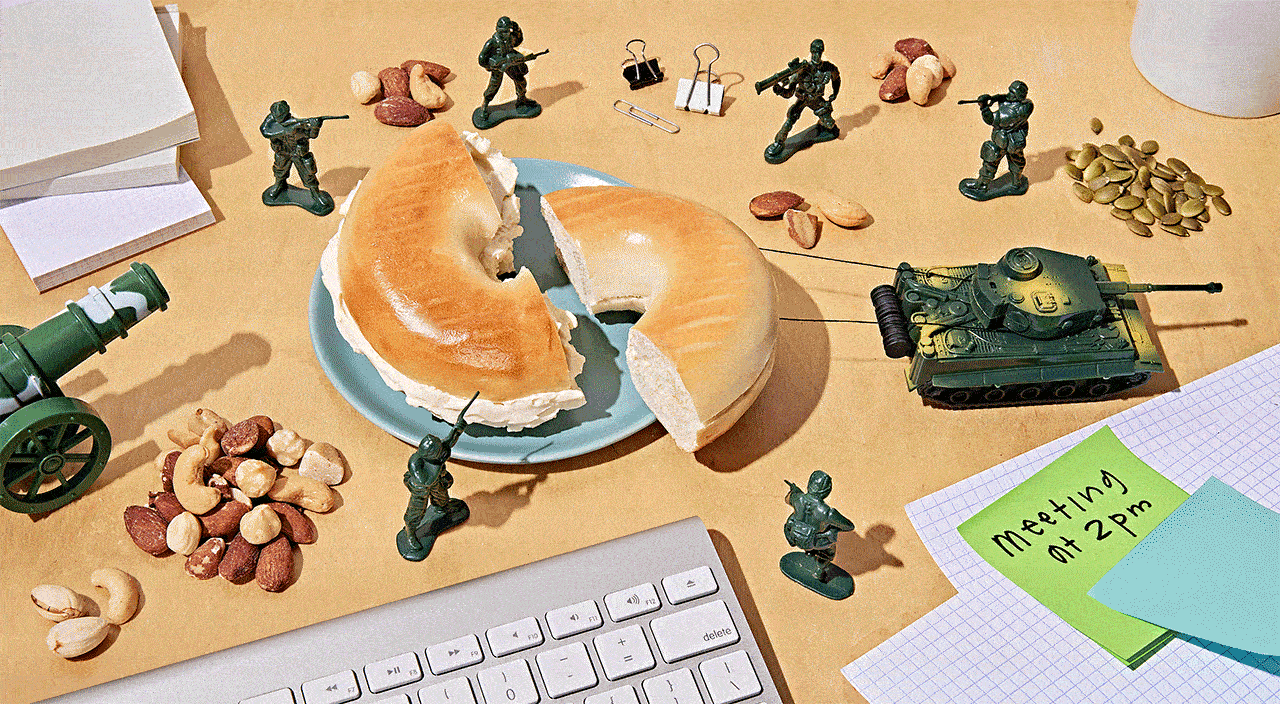 Gif of army men on desk using a tank to remove a bagel with cream cheese.