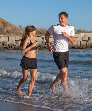 Father and daughter running along the seashore.