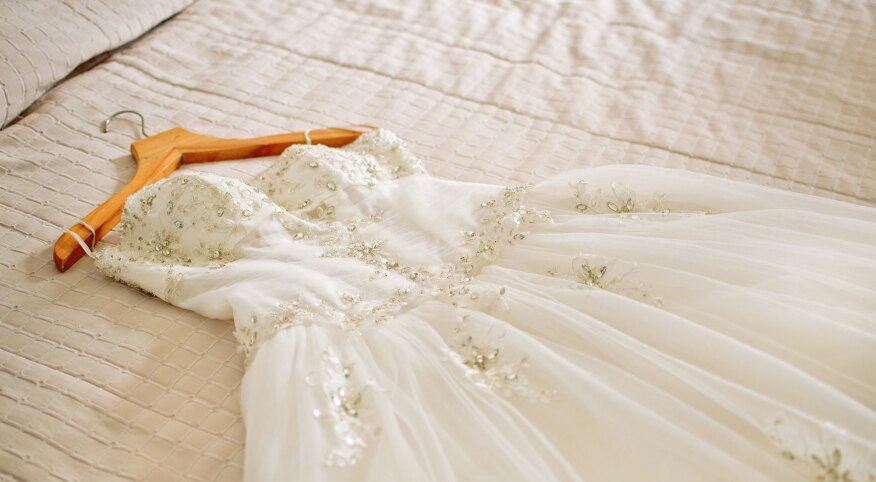 White wedding dress laying on a bed