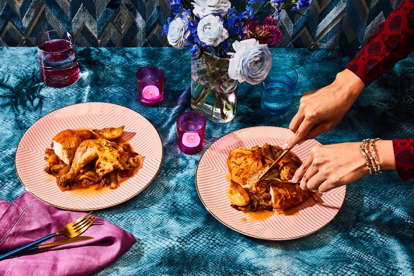 Women carving roasted chicken on pink plate