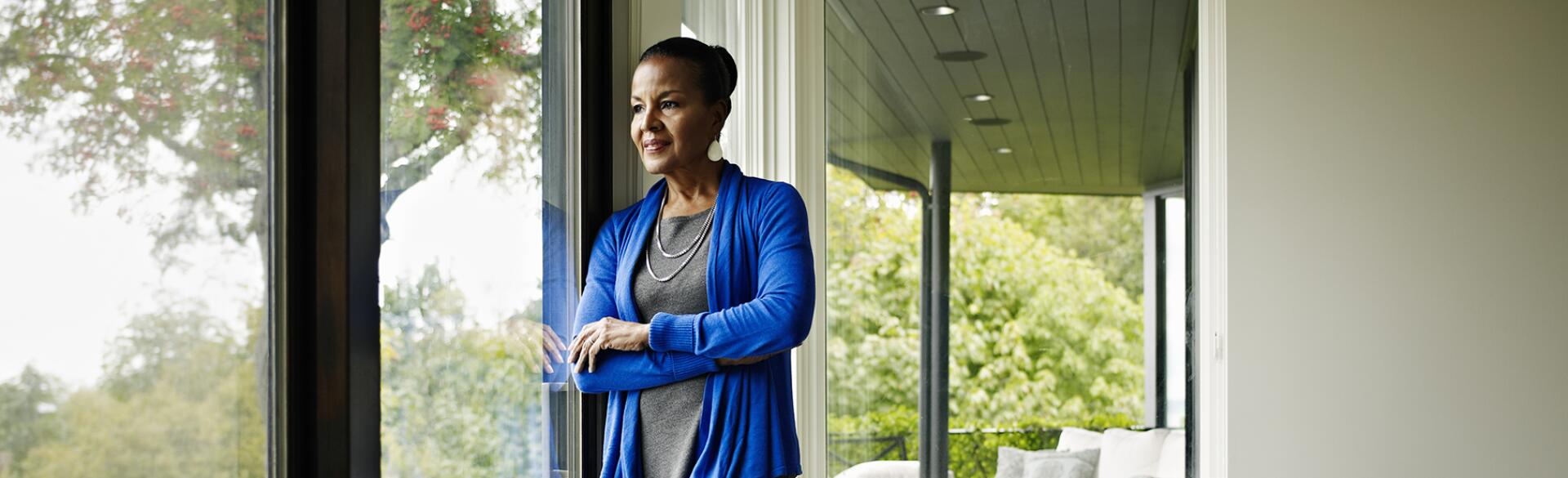 Woman standing arms crossed looking out window