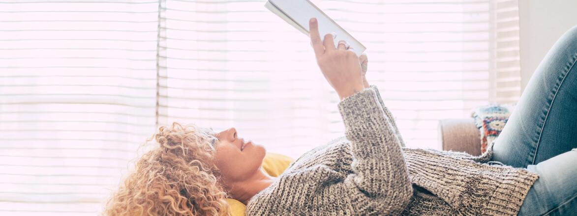 woman reading a book while lying down on a couch