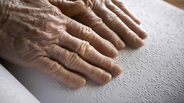 Old womans hands, reading a book with braille language