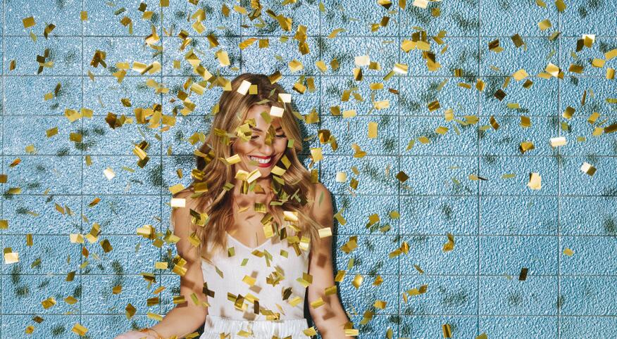 Single woman smiling with confetti falling down around her