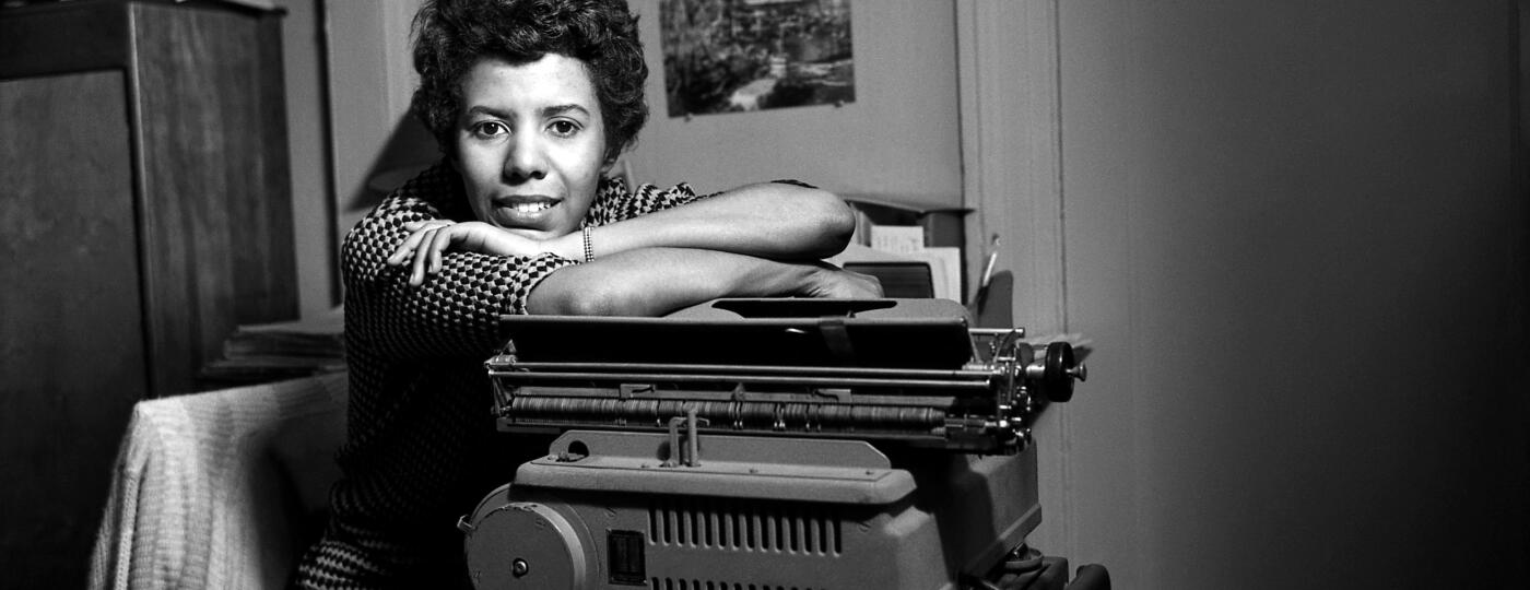 Black and white photo of Lorraine Hansberry leaning on a typewriter.