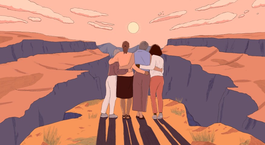 Grouping of 4 women hugging and looking at a sunset together