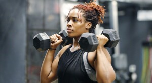 Fit, young African American woman working out with hand weights in a fitness gym.