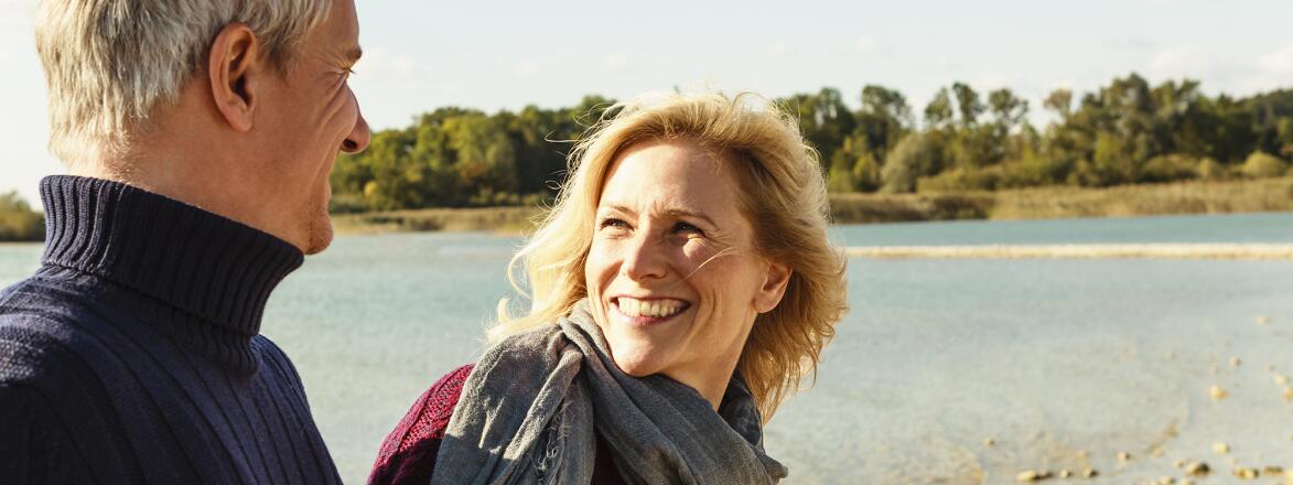Mature couple beside lake, smiling