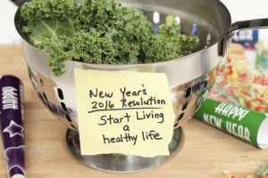 New Years 2016 resolution reminder note to start living a healthy lifestyle taped to a colander filled with fresh kale. Party horn blower and confetti add a festive feel to the image. Shot in studio with Canon 5D Mark II DSLR camera.